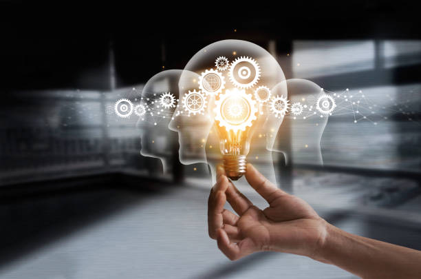 This image shows an innovation mindset concept by a hand holding light bulb and cog inside. Idea and imagination. Creative and inspiration. Innovation gears icon with network connection on human heads on metal texture background. Innovative technology in science and industrial concept.